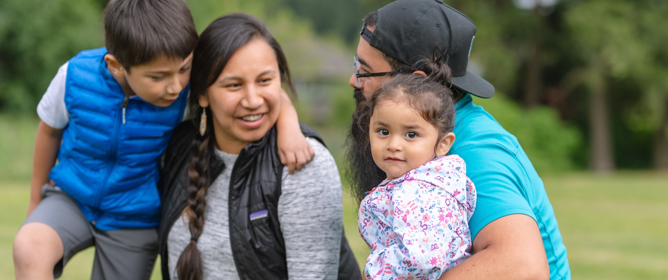 Aboriginal parents with young son and daughter outdoors.