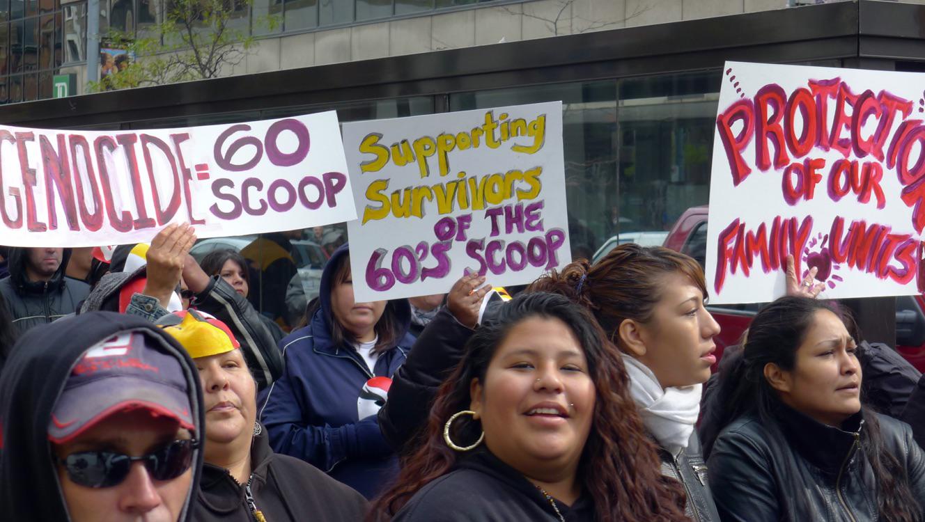 People holding signs marching in a Sixties Scoop protest.