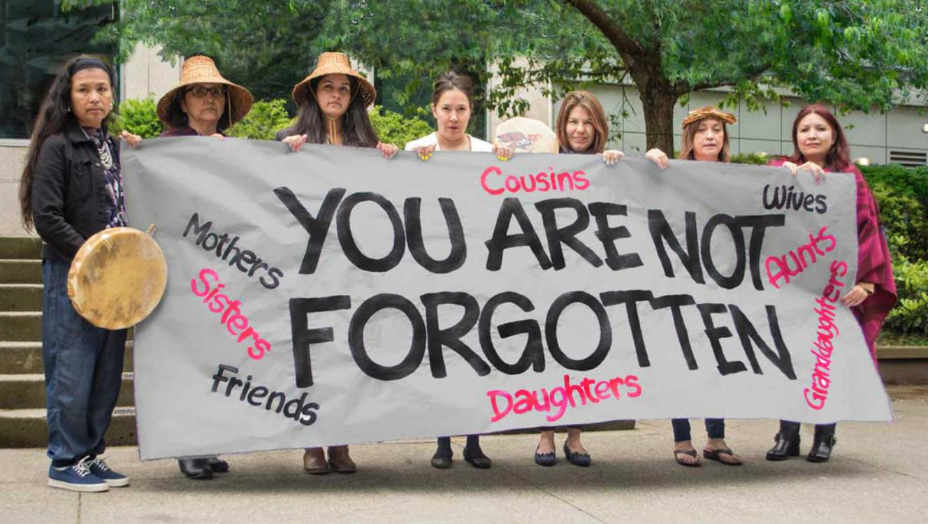 Seven women holding a hand-painted sign that says You are not forgotten.