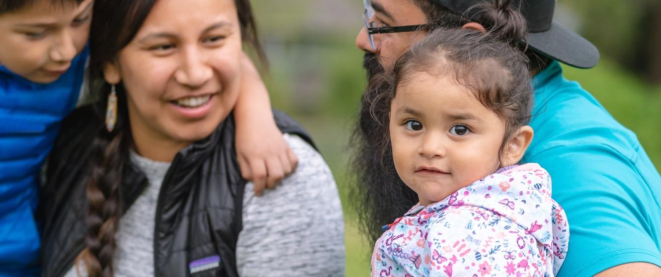 Aboriginal parents with young son and daughter outdoors.